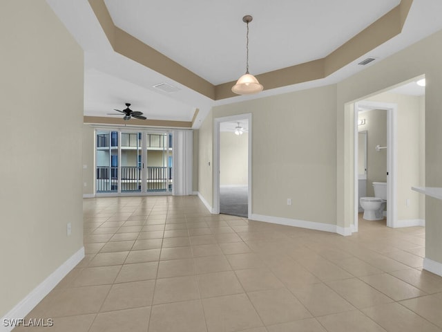 spare room featuring ceiling fan, light tile patterned flooring, and a raised ceiling