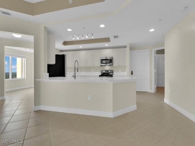 kitchen featuring sink, light tile patterned floors, a tray ceiling, white cabinetry, and stainless steel appliances