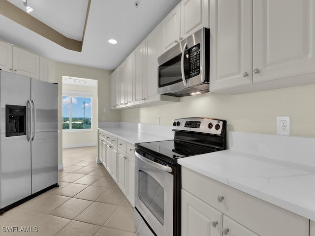 kitchen featuring white cabinets, light stone counters, light tile patterned floors, and stainless steel appliances