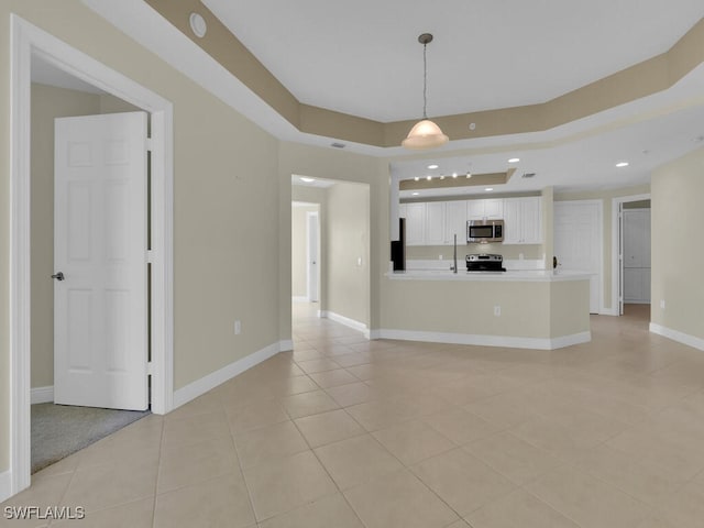 unfurnished living room with a tray ceiling, sink, and light tile patterned floors