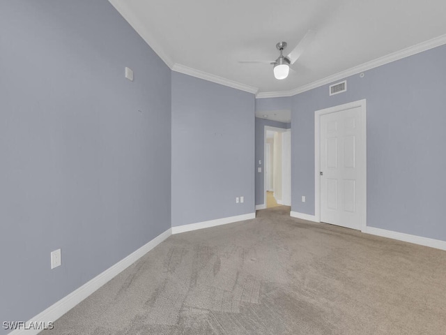 empty room with ceiling fan, light colored carpet, and crown molding