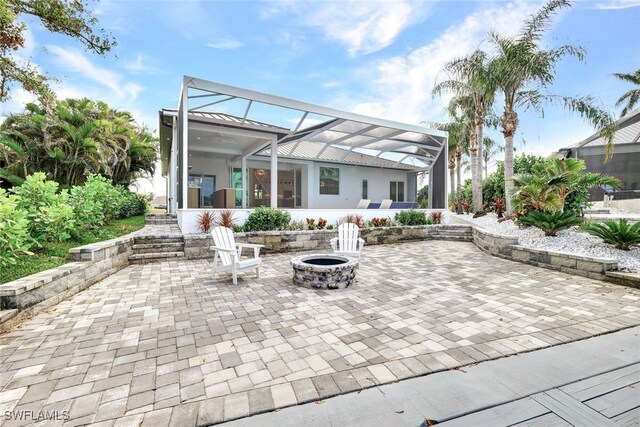 view of patio / terrace featuring glass enclosure and an outdoor fire pit