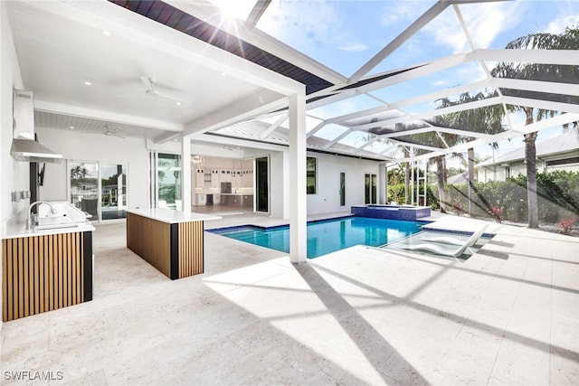 view of swimming pool with sink, ceiling fan, a lanai, an in ground hot tub, and a patio area