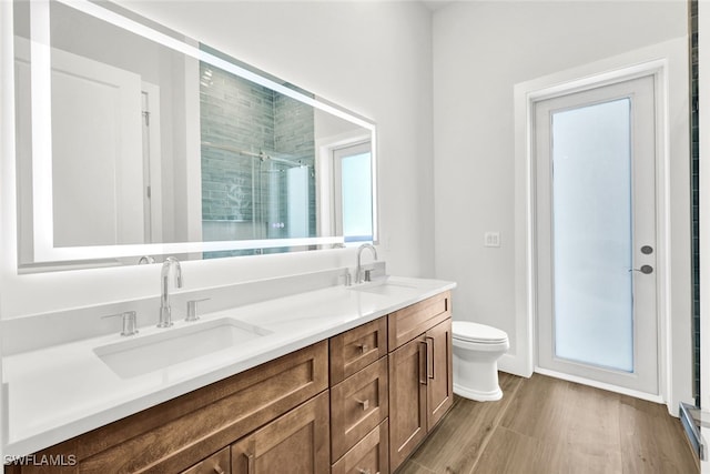 bathroom featuring vanity, toilet, wood-type flooring, and a shower with shower door