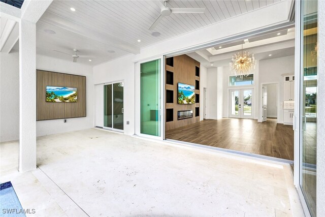 unfurnished living room with beamed ceiling, french doors, ceiling fan with notable chandelier, and wood ceiling