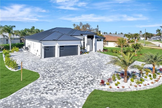 view of front of property with a front lawn, decorative driveway, metal roof, and an attached garage