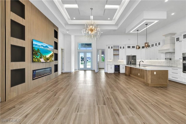 interior space featuring a sink, french doors, light wood finished floors, and a raised ceiling