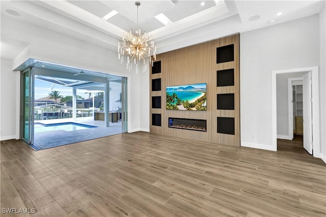 unfurnished living room with a raised ceiling, a towering ceiling, light wood-style floors, a large fireplace, and a sunroom