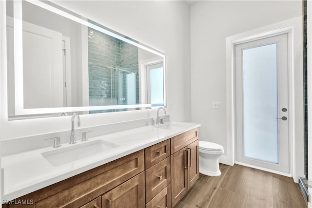 bathroom featuring a stall shower, a sink, toilet, and double vanity