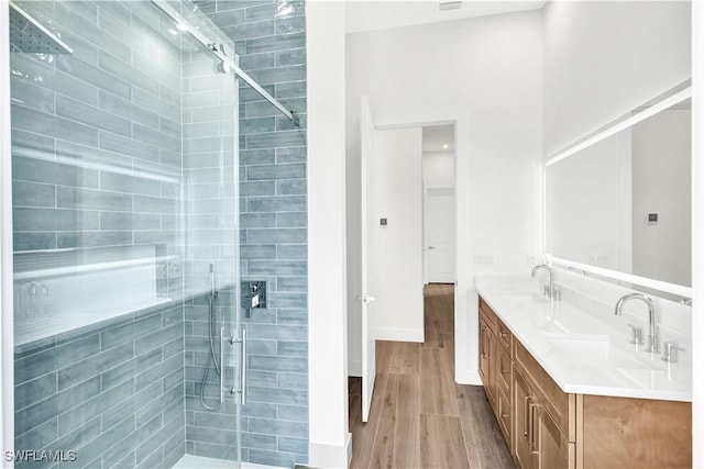 full bath with double vanity, wood finished floors, a stall shower, and a sink