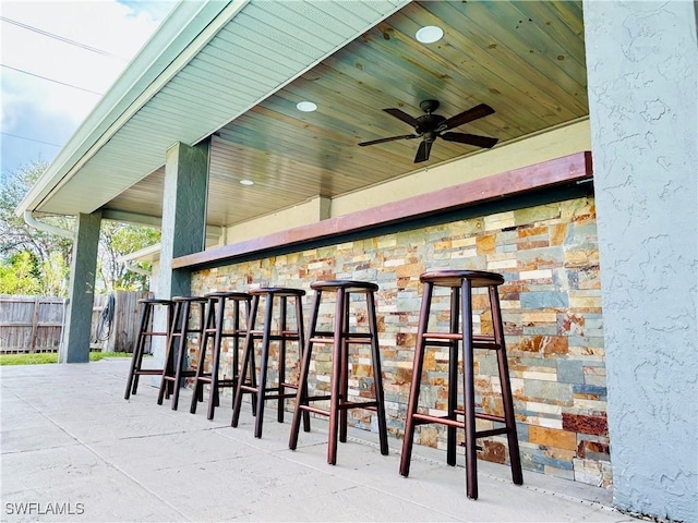 view of patio with ceiling fan and a bar