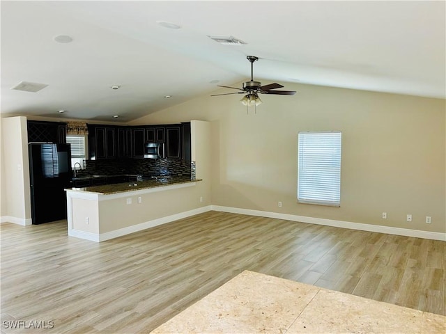 kitchen featuring tasteful backsplash, black fridge, ceiling fan, light hardwood / wood-style floors, and lofted ceiling