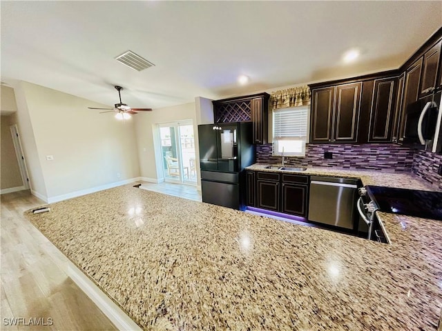 kitchen with sink, decorative backsplash, dark brown cabinets, light stone counters, and stainless steel appliances