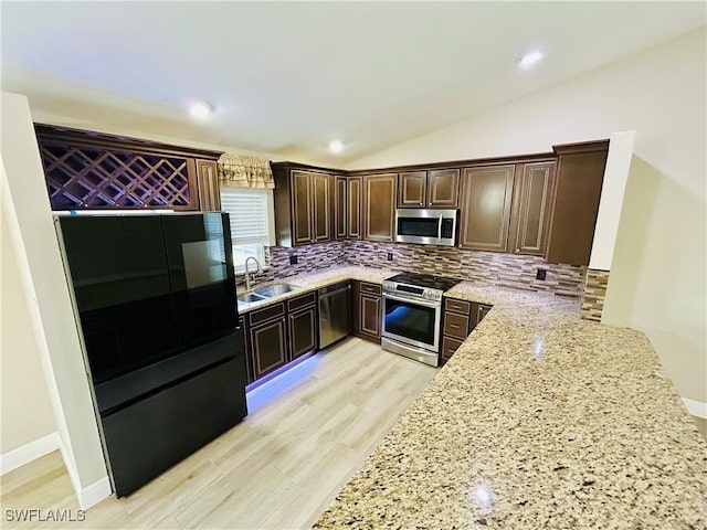 kitchen with sink, decorative backsplash, light stone countertops, appliances with stainless steel finishes, and dark brown cabinets