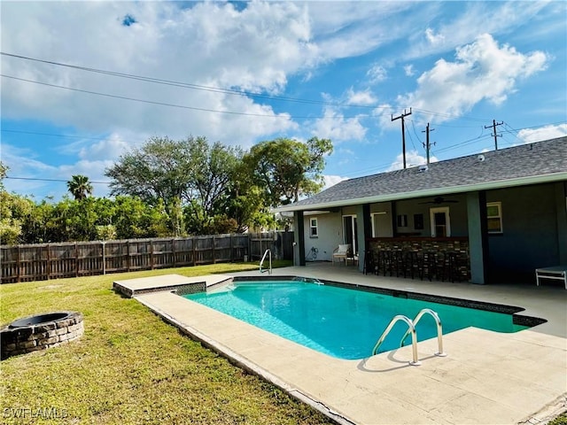 view of swimming pool featuring ceiling fan, an outdoor fire pit, a patio area, and a lawn