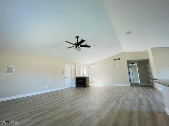 unfurnished living room featuring ceiling fan with notable chandelier, lofted ceiling, and light hardwood / wood-style flooring