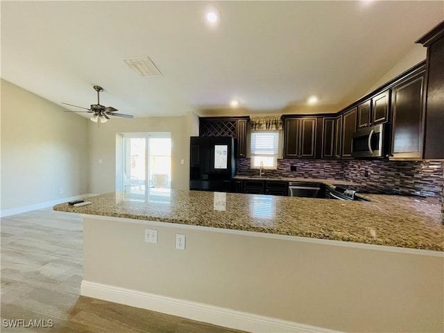 kitchen featuring backsplash, sink, ceiling fan, light stone counters, and stainless steel appliances