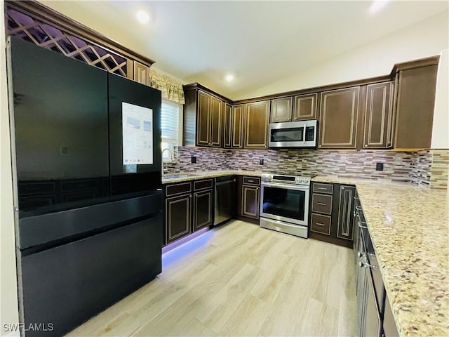 kitchen with dark brown cabinets, light stone countertops, appliances with stainless steel finishes, and vaulted ceiling