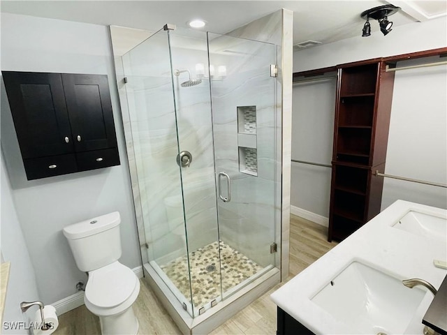 bathroom featuring wood-type flooring, vanity, toilet, and a shower with door