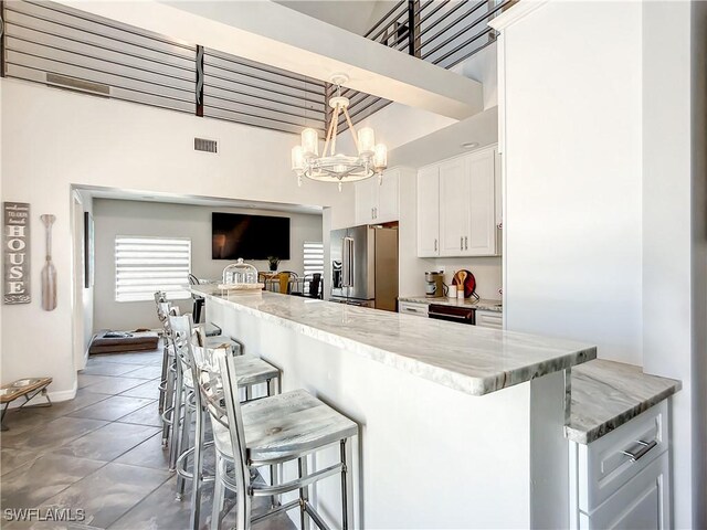 309 Donora Blvd, Fort Myers Beach, FL 33931 - kitchen featuring high end refrigerator, white cabinets, a kitchen breakfast bar, light stone countertops, and pendant lighting