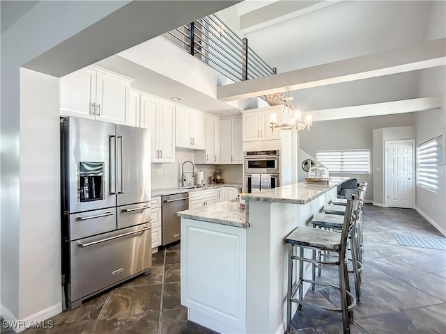 309 Donora Blvd, Fort Myers Beach, FL 33931 - kitchen with light stone counters, stainless steel appliances, a sink, a kitchen island, and white cabinetry