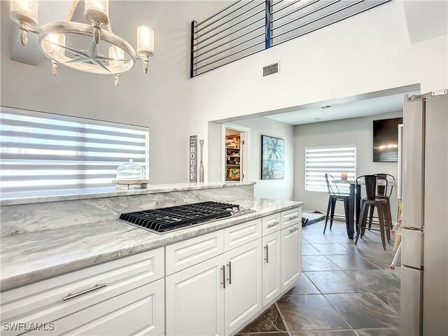 309 Donora Blvd, Fort Myers Beach, FL 33931 - kitchen featuring a chandelier, light stone counters, stainless steel gas cooktop, white cabinets, and freestanding refrigerator
