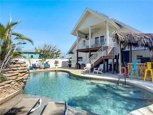 view of swimming pool with a patio, outdoor dry bar, a ceiling fan, fence, and stairs