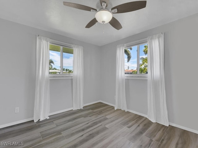 unfurnished room featuring ceiling fan, a healthy amount of sunlight, and hardwood / wood-style flooring