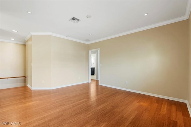 empty room with light wood-style floors, crown molding, and baseboards