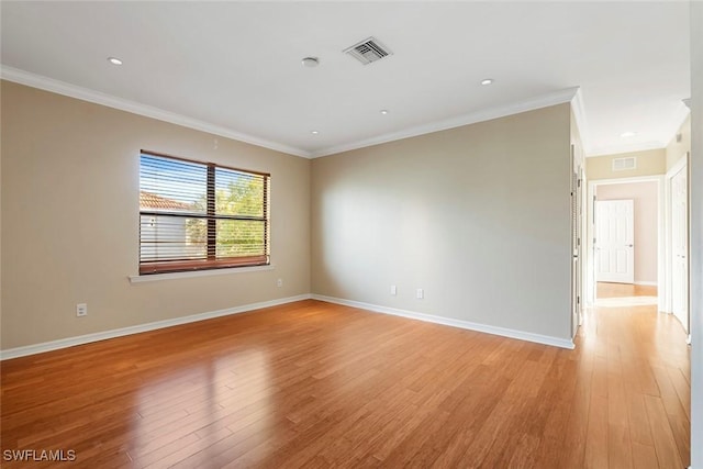 spare room with visible vents, ornamental molding, light wood-style floors, and baseboards