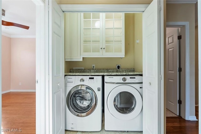 laundry area featuring washing machine and clothes dryer, crown molding, cabinet space, wood finished floors, and baseboards