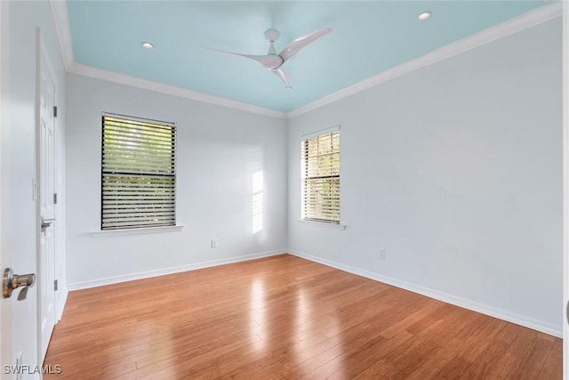 empty room featuring crown molding, ceiling fan, baseboards, and wood finished floors