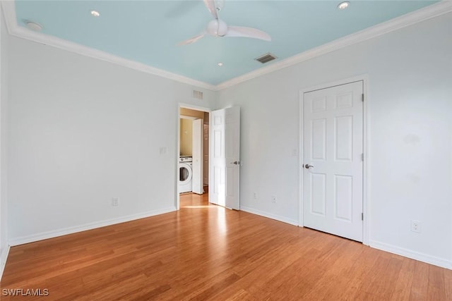 unfurnished bedroom featuring crown molding, visible vents, wood finished floors, and washer / dryer