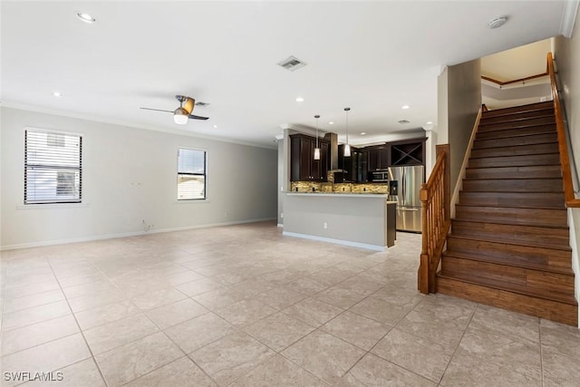 unfurnished living room featuring ceiling fan, light tile patterned floors, visible vents, ornamental molding, and stairway