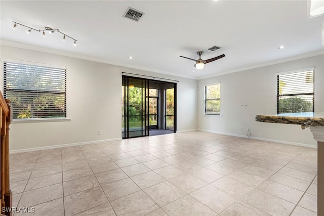 spare room with crown molding, light tile patterned floors, visible vents, and a wealth of natural light