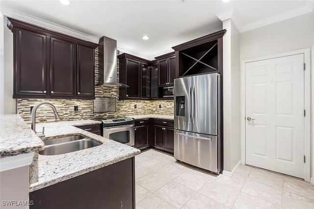 kitchen featuring decorative backsplash, light stone counters, stainless steel appliances, wall chimney range hood, and a sink