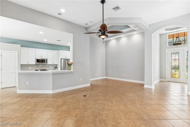 unfurnished living room featuring ceiling fan, light tile patterned flooring, and sink