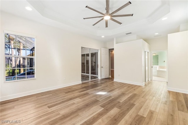 empty room with light hardwood / wood-style flooring, a raised ceiling, ceiling fan, and crown molding