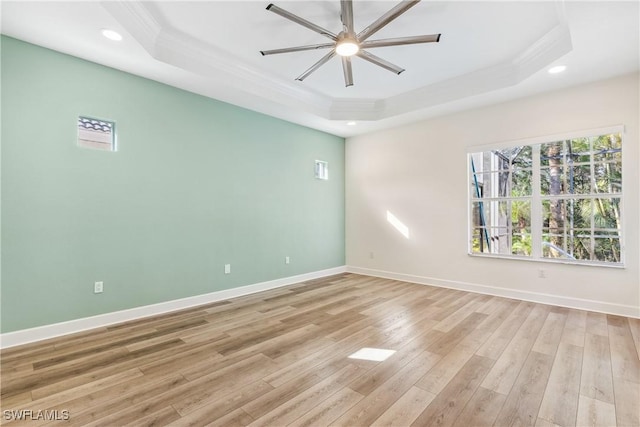 unfurnished room featuring ceiling fan, a raised ceiling, ornamental molding, and light hardwood / wood-style flooring