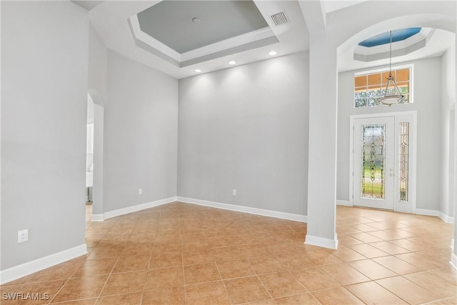 spare room featuring a high ceiling, a tray ceiling, and light tile patterned floors