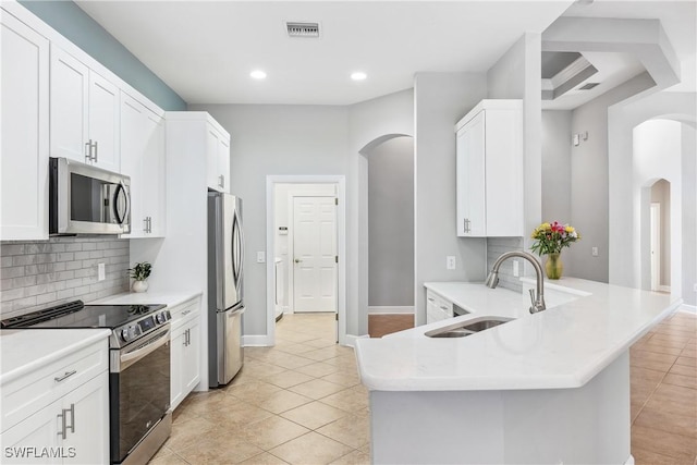 kitchen featuring kitchen peninsula, appliances with stainless steel finishes, sink, light tile patterned floors, and white cabinets