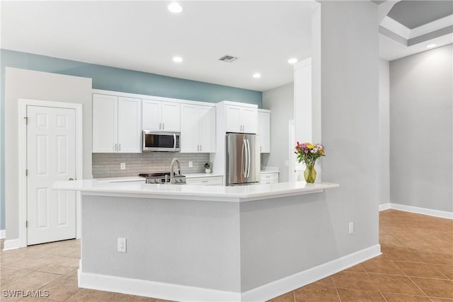 kitchen with kitchen peninsula, appliances with stainless steel finishes, tasteful backsplash, light tile patterned flooring, and white cabinetry