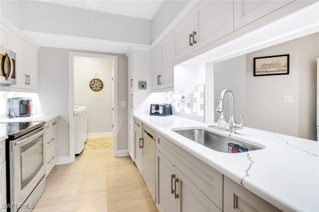 kitchen with backsplash, electric range oven, light stone counters, washing machine and clothes dryer, and white cabinetry