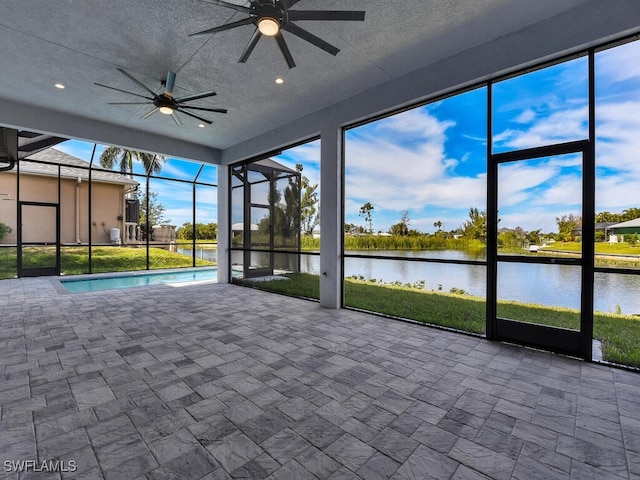 unfurnished sunroom featuring a water view, a swimming pool, and ceiling fan