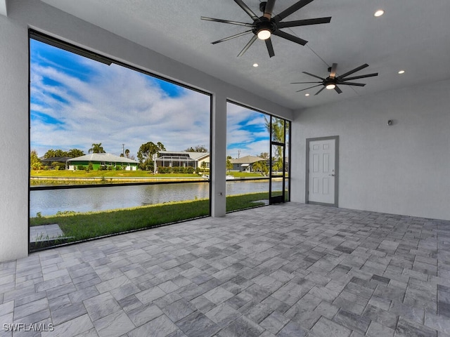 unfurnished sunroom featuring a water view and ceiling fan