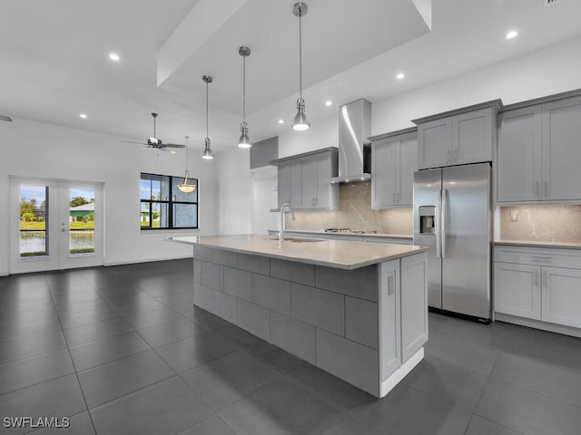 kitchen with sink, tasteful backsplash, stainless steel fridge with ice dispenser, gray cabinets, and wall chimney range hood