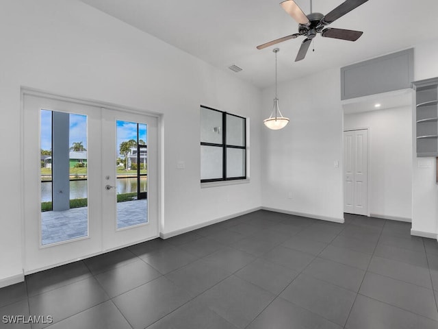 spare room with a water view, ceiling fan, and french doors