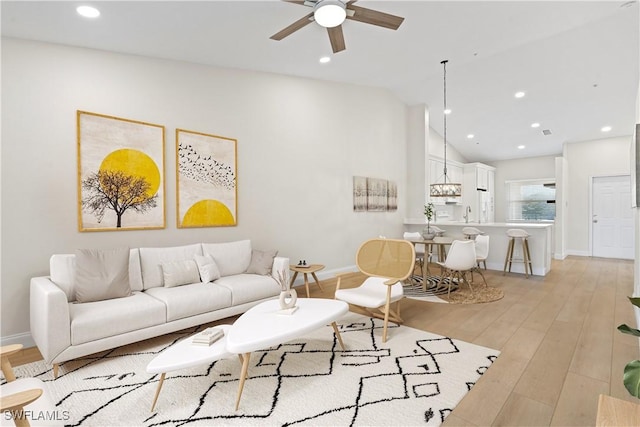 living room with light wood-type flooring, vaulted ceiling, and ceiling fan