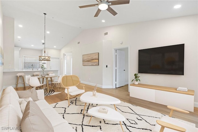 living room featuring ceiling fan, lofted ceiling, and light wood-type flooring