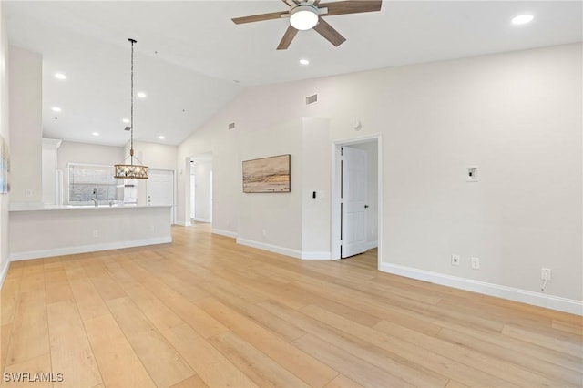 unfurnished living room featuring ceiling fan, sink, light hardwood / wood-style floors, and lofted ceiling